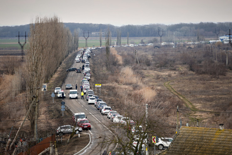 People walk next to a row of cars waiting to pick up family members and refugees fleeing the war in Ukraine, in Palanca, Moldova, Wednesday, March 2, 2022. Russian forces have escalated their attacks on crowded cities in what Ukraine's leader called a blatant campaign of terror. (AP Photo/Aurel Obreja)